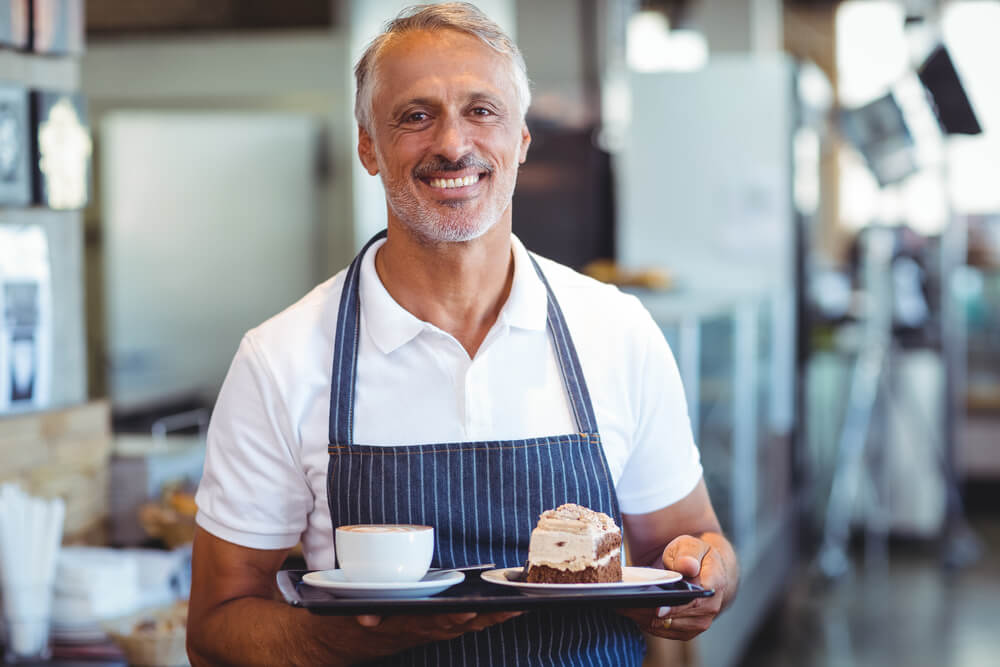 waiter smiling and holding tray at the coffee shop