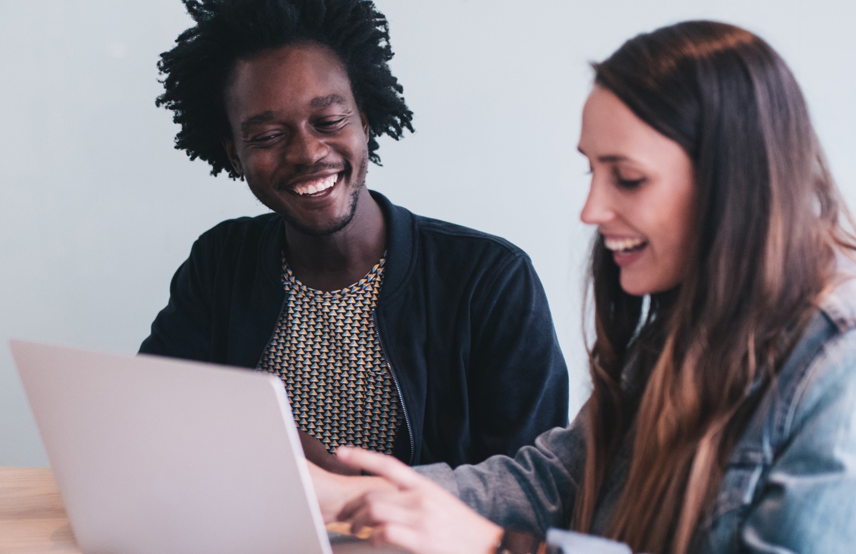 Two young adults smiling at laptop