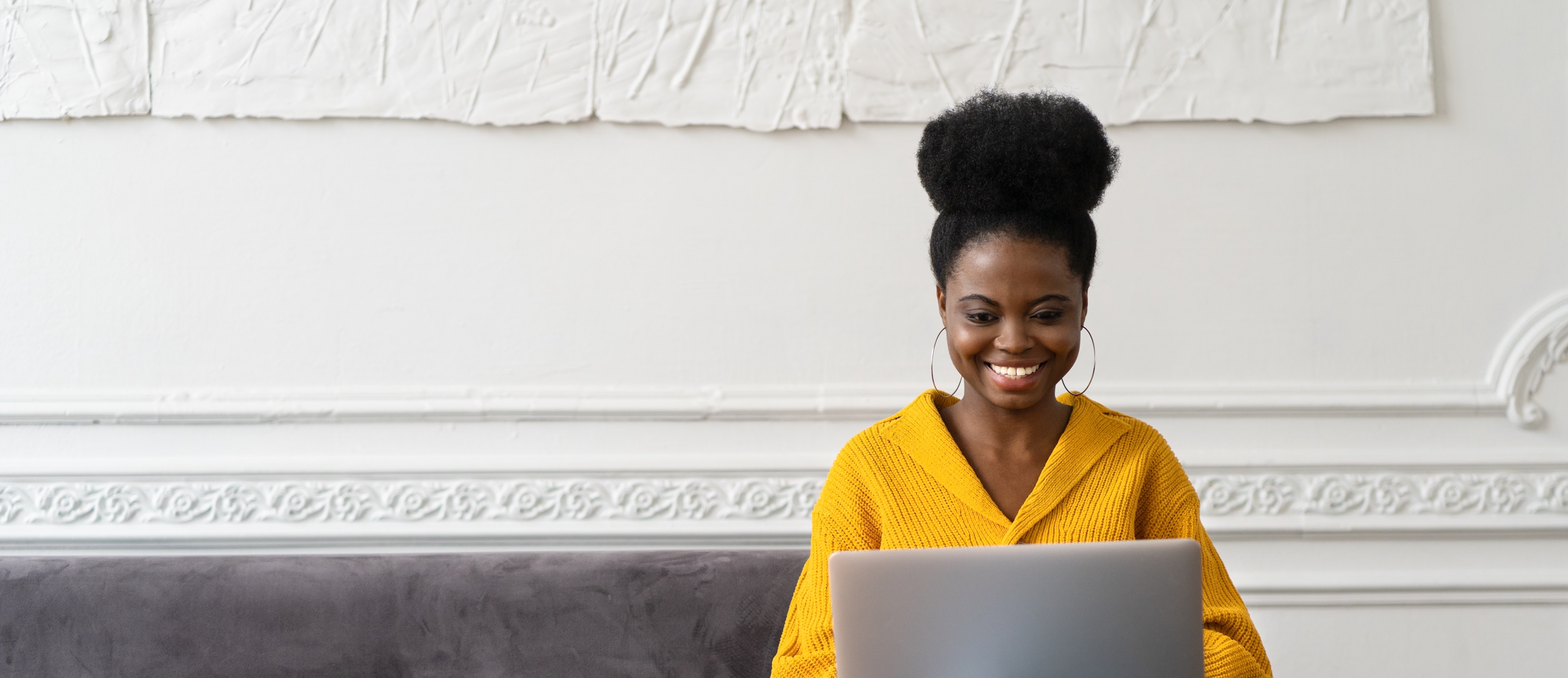 smiling-african-american-millennial-woman-with-afro-hairstyle-wear-yellow-cardigan-sitting-on-sofa_t20_LlnRLo